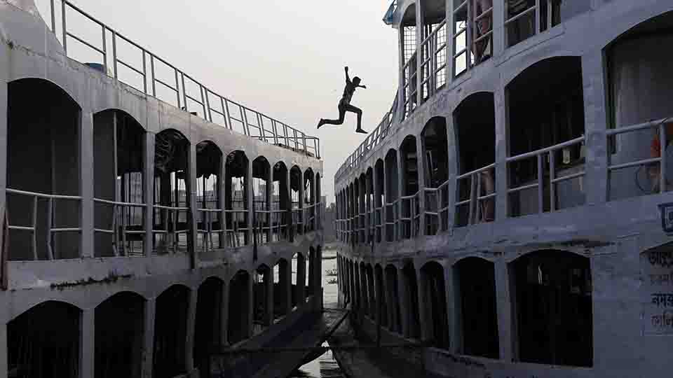 A man jumps from a boat to another by the river Buriganga in Dhaka October 16, 2012.