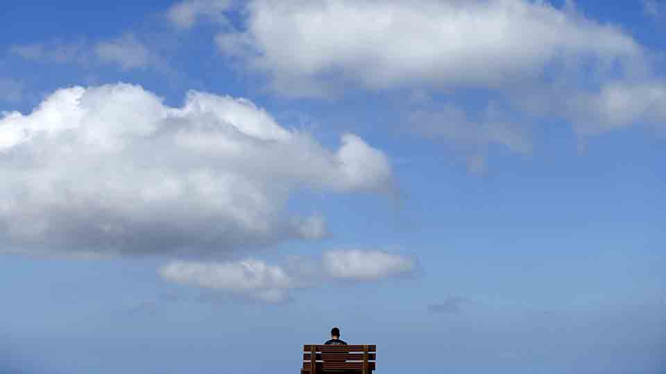 A young man sits high atop a hill reading a book on a park beach as the clouds pass overhead in San Marco, California March 23, 2015.