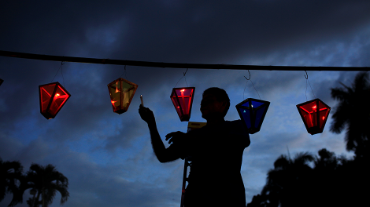 Um homem acende velas durante o Festival das Lanternas celebrando a véspera da natividade da Virgem Maria em Ahuachapan, El Salvador